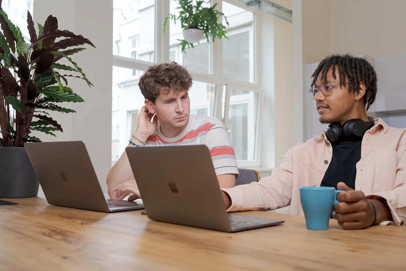 Dois desenvolvedores trabalhando lado a lado com laptops em ambiente colaborativo de software-house