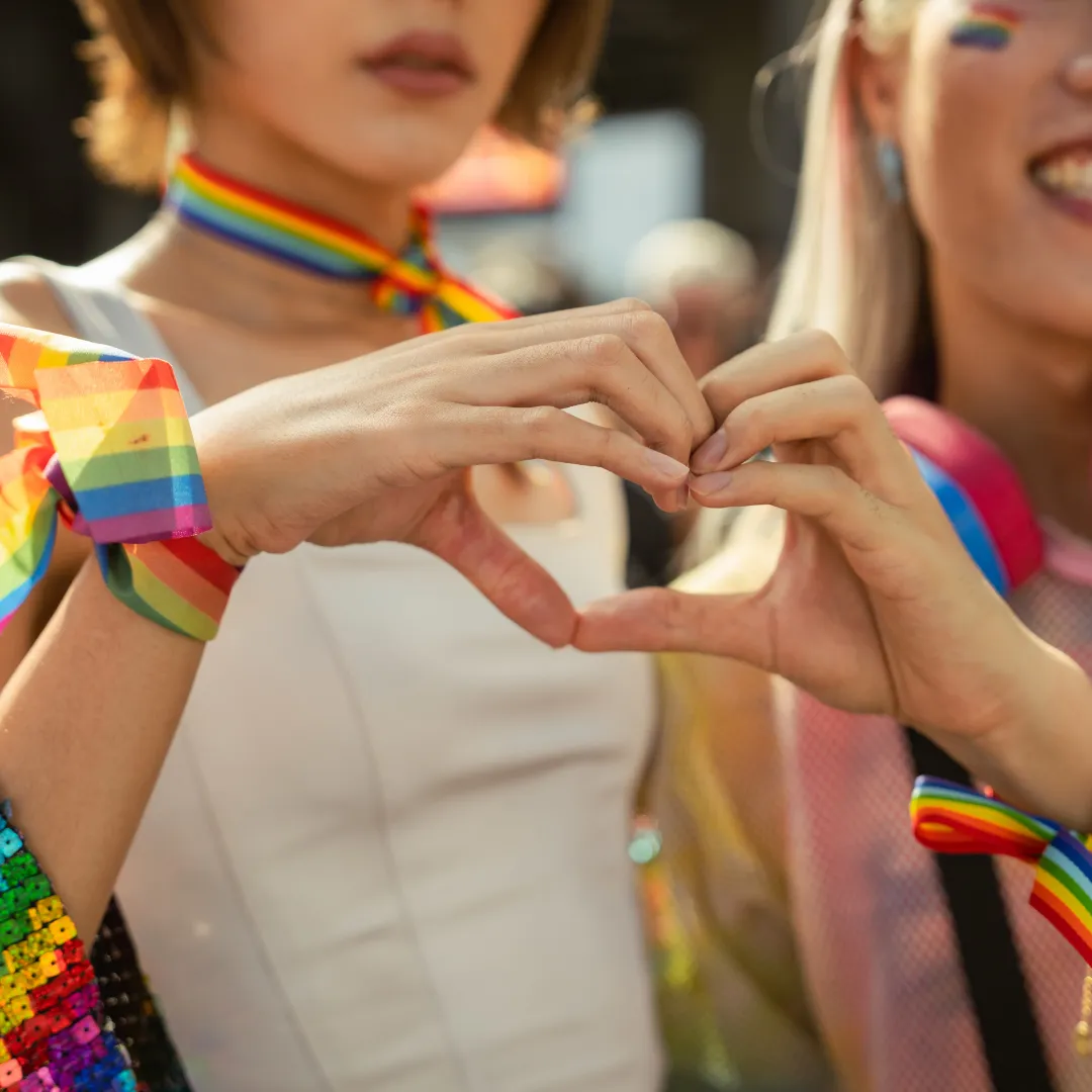 Duas mulheres LGBTQIA+ fazendo um coração com as mãos — representatividade no mercado de trabalho